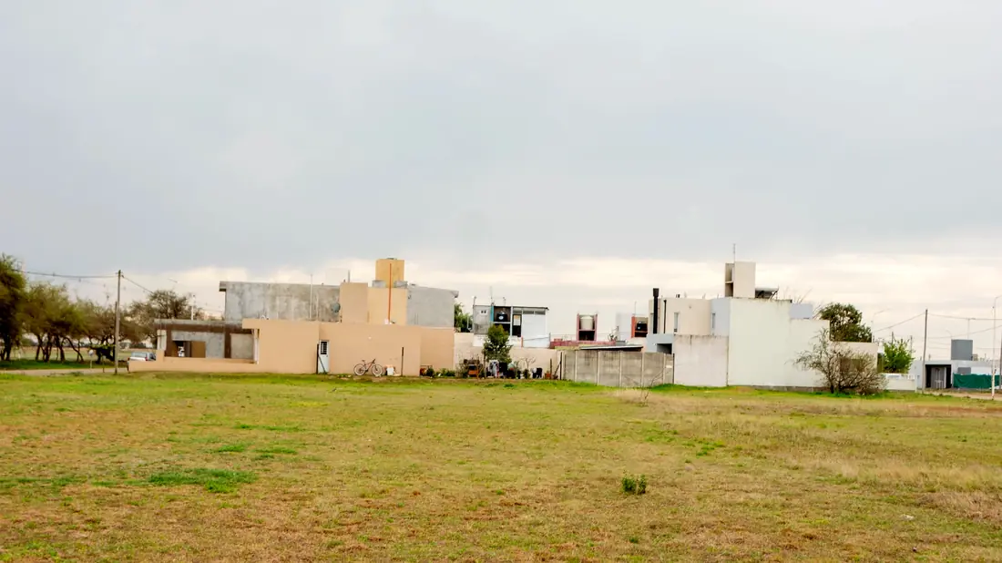 Amplio espacio verde con viviendas al fondo